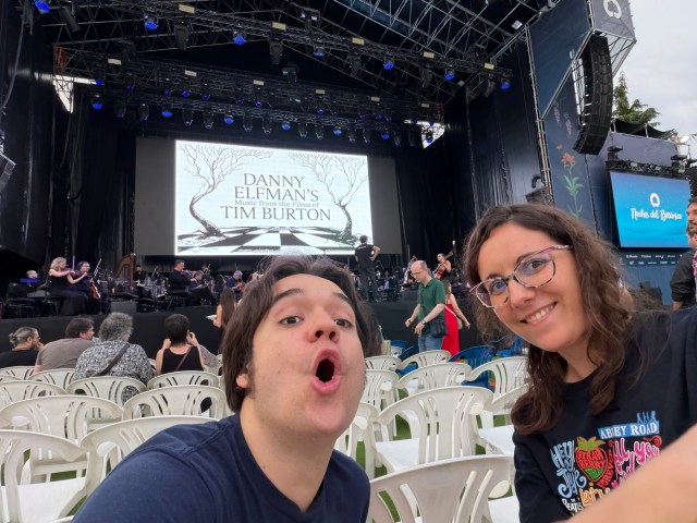 Leti y Alberto esperando al inicio de la función con el título de la misma en una pantalla al fondo